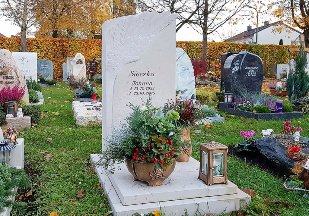 Urnengrabstein mit Einfassung und Abdeckplatte aus Kalkstein - gehauener Engelsflügel & Grabschmuck aus Bronze - Friedhof Vaterstetten