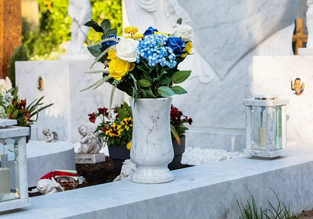 Eine Marmorgrabvase, gefüllt mit bunten Rosen, bringt im Frühling lebendige Farben und Eleganz auf das Grab.