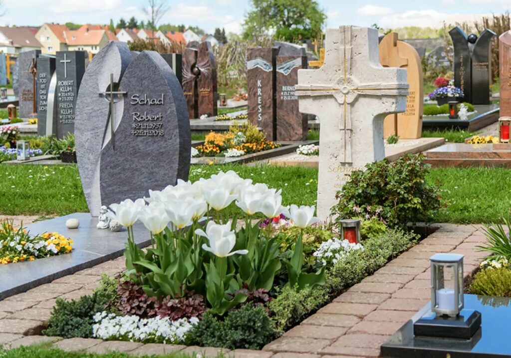 Verziertes Grabkreuz aus hellem Kalkstein mit Vergoldung - Grabgestaltung im Frühjahr - Friedhof Neuhof