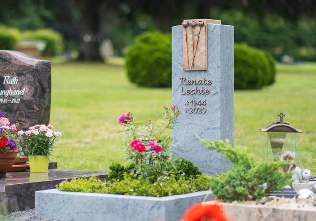 Grabstein mit Bronzelement für ein Urnengrab aus Granit mit Einfassung - Moderne Grabbepflanzung im Sommer mit Blumen