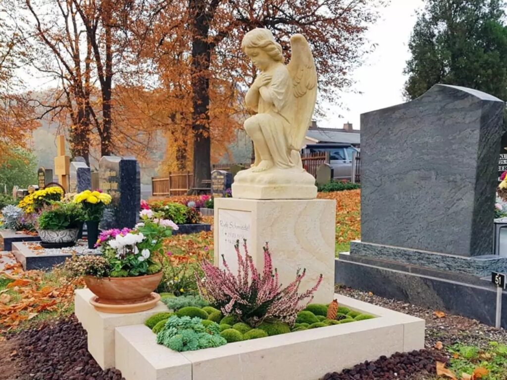 Grabanlage für ein Urnengrab mit einem Grabstein aus Sandstein, verziert mit einem Engel.