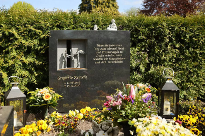 Polierter Doppelgrabstein  modernes Design  aus schwarzem Granit mit Öffnung und Engelfiguren aus Bronze - Grabgestaltung mit Frühlingsblühern und Grabdekoration