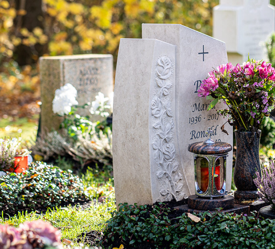 Kleines Urnengrabmal aus hellem Kalkstein mit Rosenmotiv