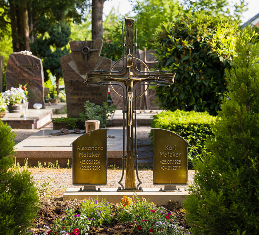 Klassische Doppelgrabanlage mit Grabkreuz aus geschmiedetem Eisen und beschrifteten Bronzetafeln