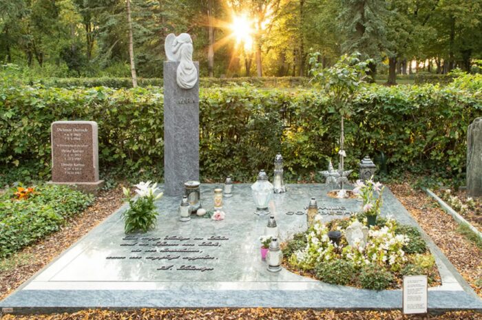 Familiengrabanlage mit einer Engel-Stele und großer Abdeckplatte. Auf der Grabplatte stehen viele kleine Grablaternen und Grablichter als Dekoration.